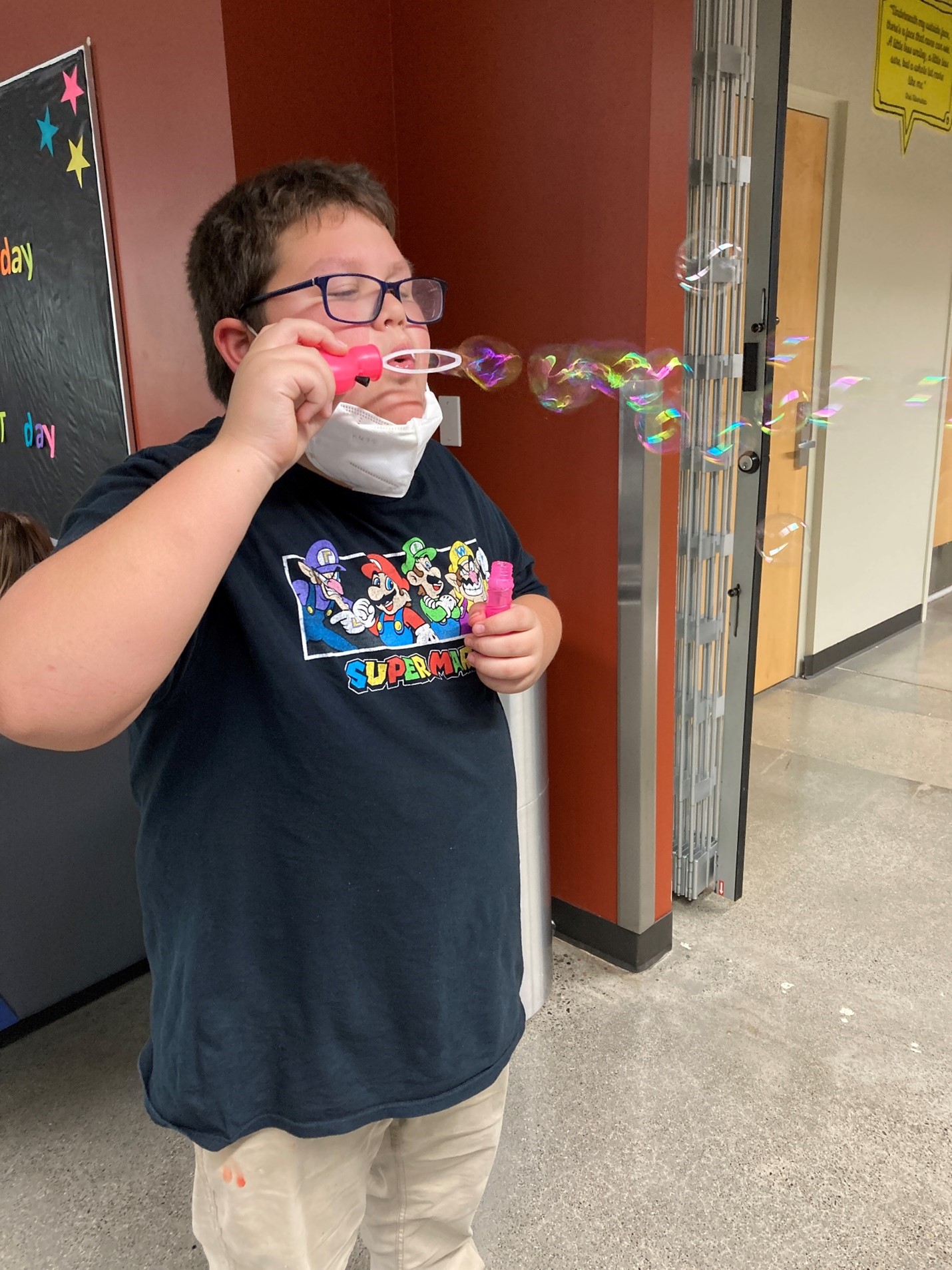 Photo of a kid blowing bubbles with their mask down